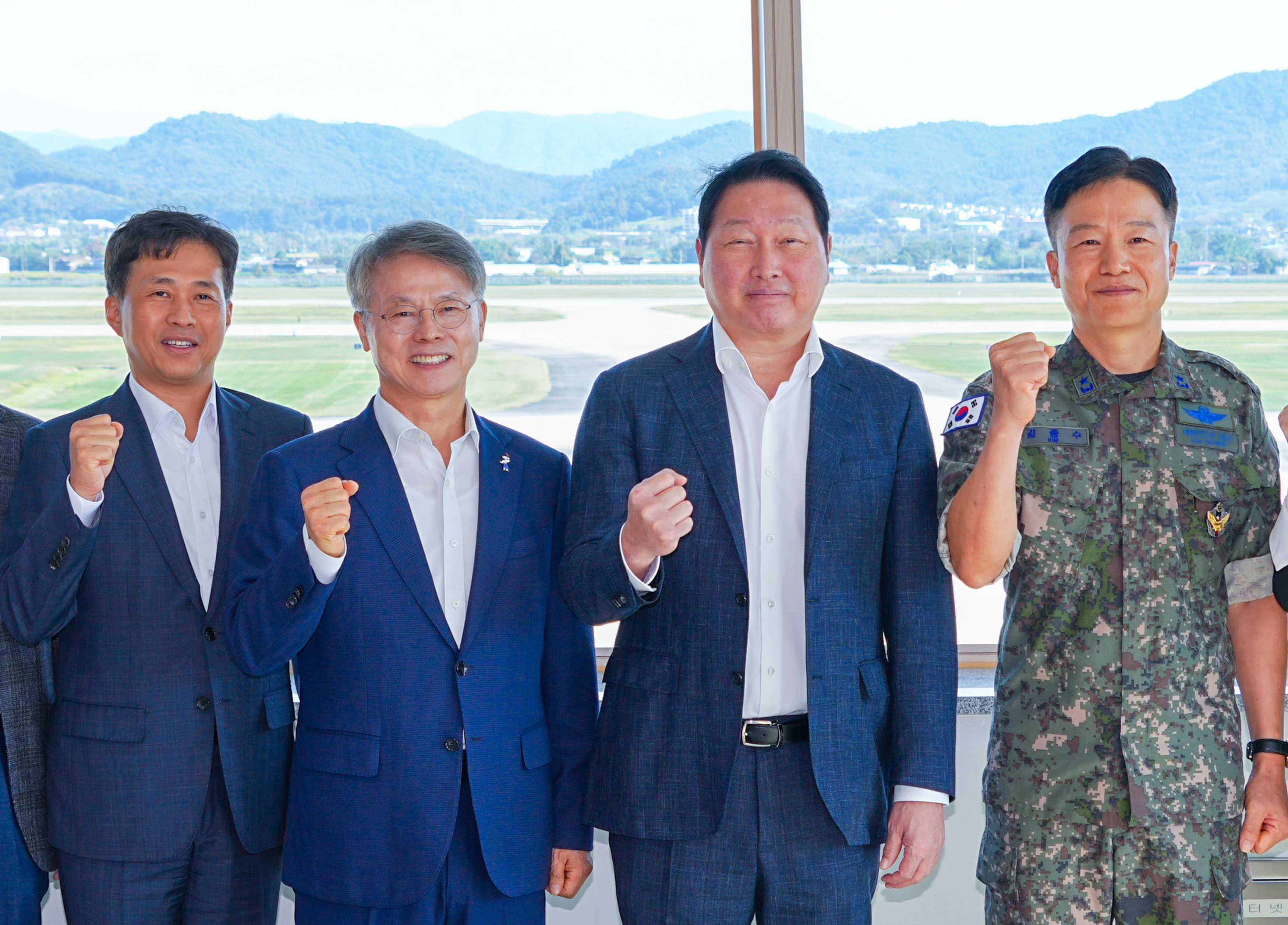 민형배 전남광주통합특별시장과 최태원 SK그룹 회장이 9일 오후 광산구 공군 제1전투비행단 비상관제탑에서 호남권 반도체 클러스터 부지를 점검한 뒤 기념촬영을 하고 있다./전남광주통합특별시 제공